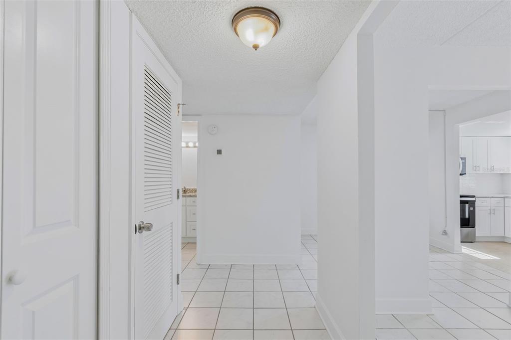 A white-tiled hallway leads to a bathroom and a kitchen with white cabinets — 1062 85TH TERRACE N UNIT A, ST PETERSBURG, FL