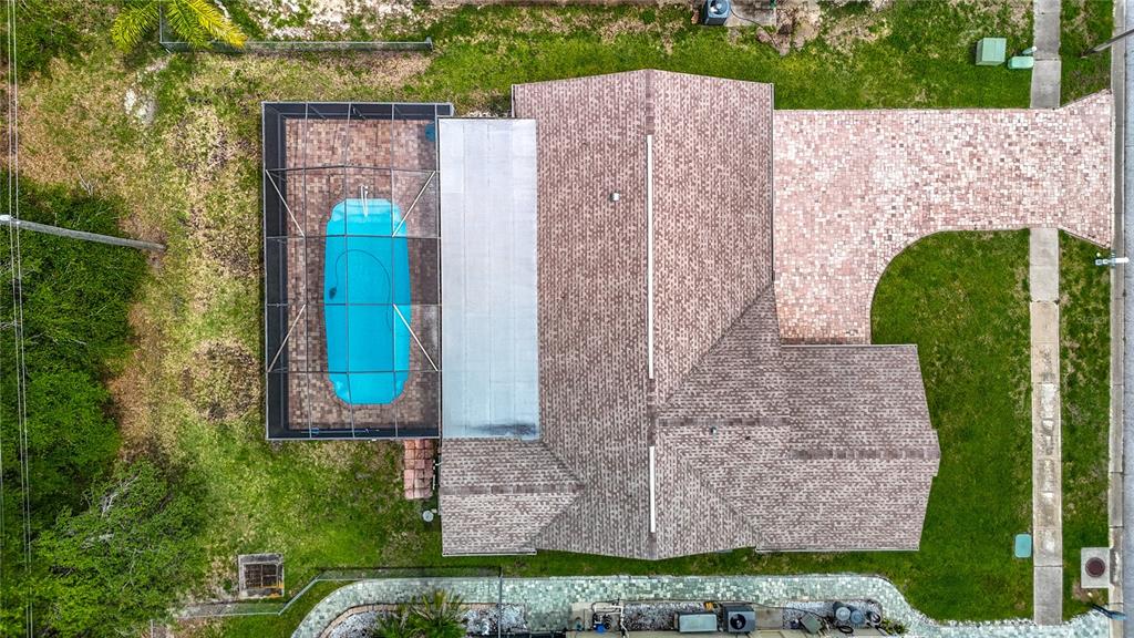 An aerial view shows a house with a paved driveway, a pool, and a screened enclosure — 18817 PARADE ROAD, HUDSON, FL