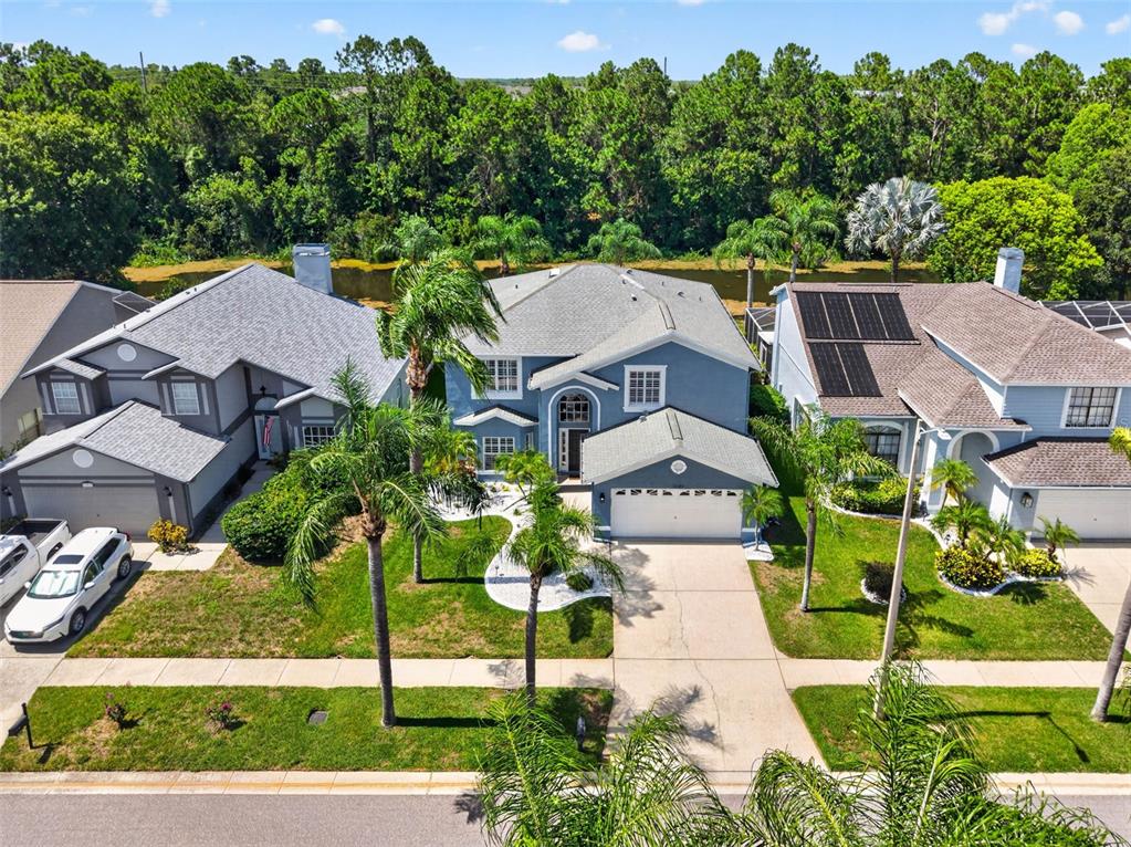 An aerial view shows three suburban houses with gray roofs and driveways near a wooded area — 11123 CLAYRIDGE DRIVE, TAMPA, FL