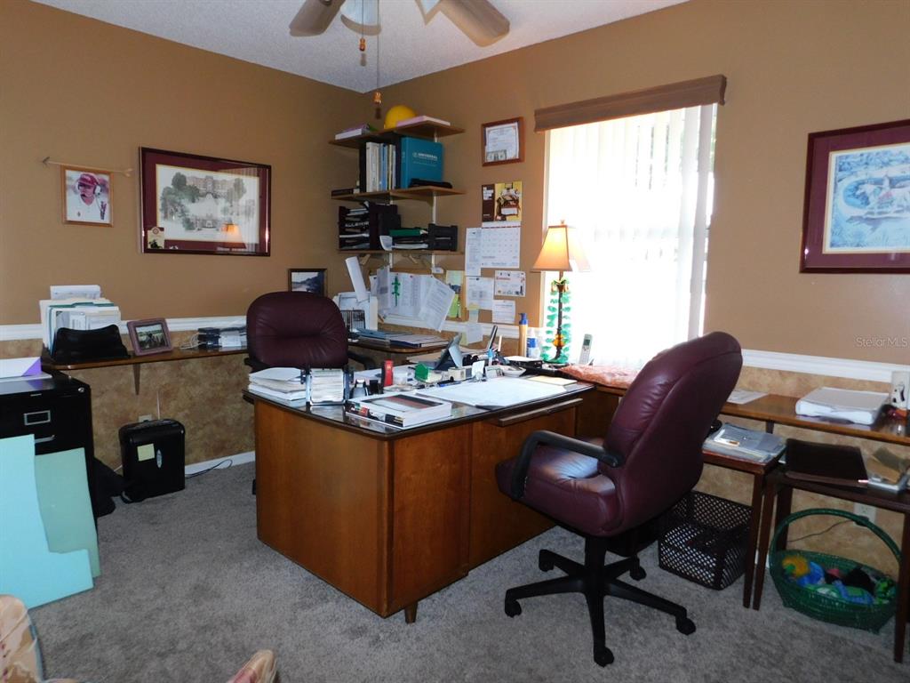 A home office features a wooden desk, two rolling chairs, wall shelving, and a window — 4655 N CARL G. ROSE HIGHWAY, HERNANDO, FL