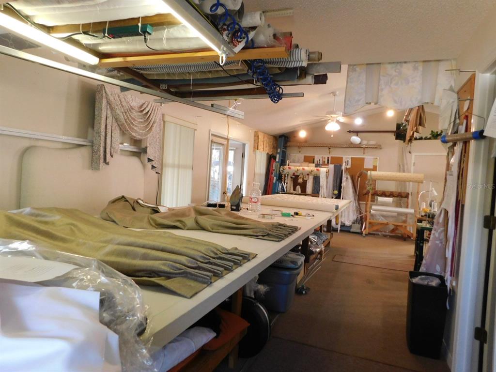 A sewing or craft workshop features a large work table, fabric rolls, and hanging curtains — 4655 N CARL G. ROSE HIGHWAY, HERNANDO, FL