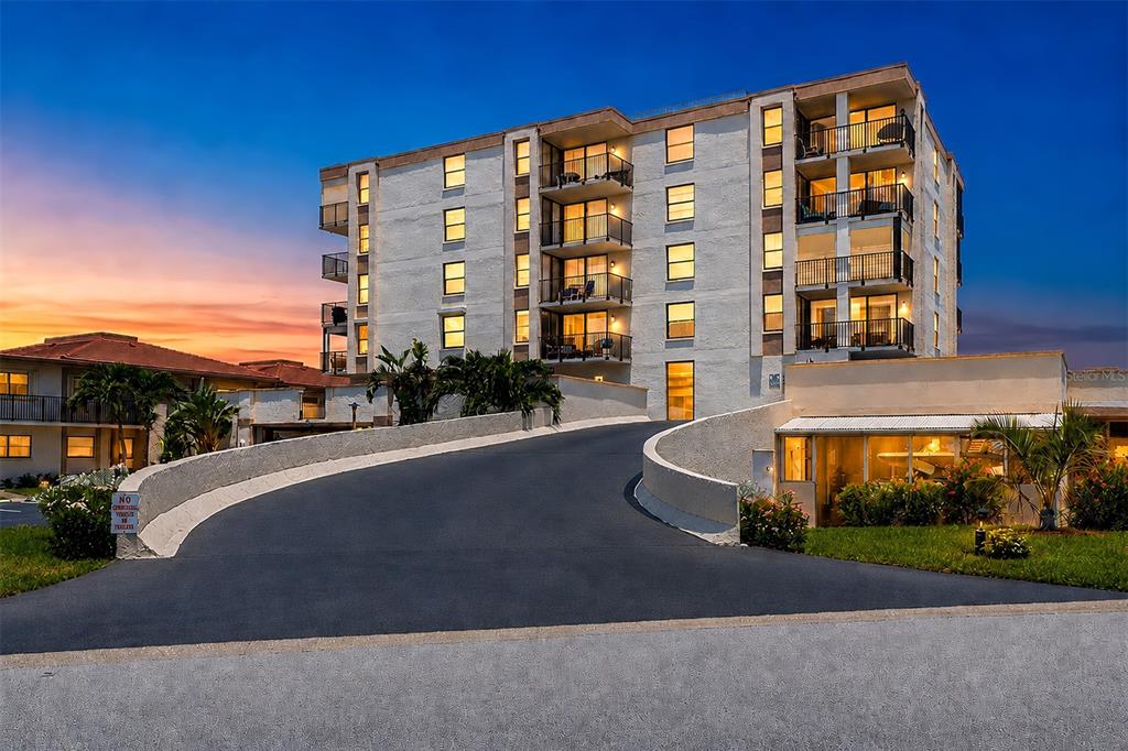 A multi-story apartment building with balconies and a curved driveway at sunset — 6145 SUN BOULEVARD UNIT 306, ST PETERSBURG, FL