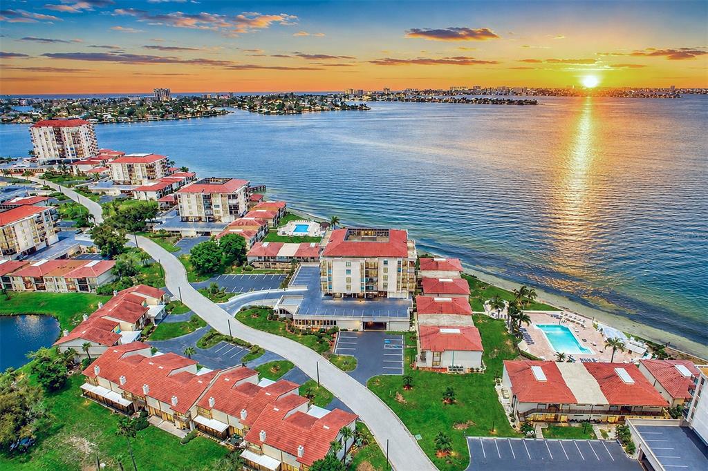 An aerial view of a waterfront apartment complex with red-tiled roofs at sunset — 6145 SUN BOULEVARD UNIT 306, ST PETERSBURG, FL