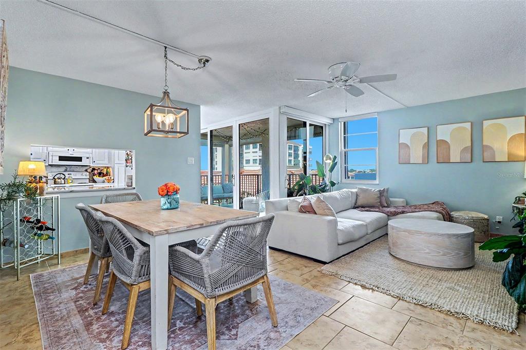 An open-concept living and dining area features light blue walls, tile flooring, and a balcony — 6145 SUN BOULEVARD UNIT 306, ST PETERSBURG, FL