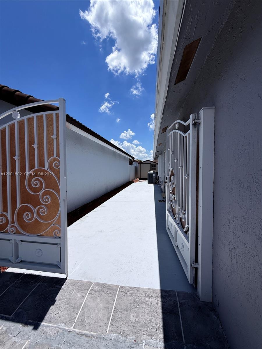 A paved side yard features white metal gates and a small storage shed in the distance — 14220 SW 53rd St # B, Miami FL 33175, MIAMI, FL