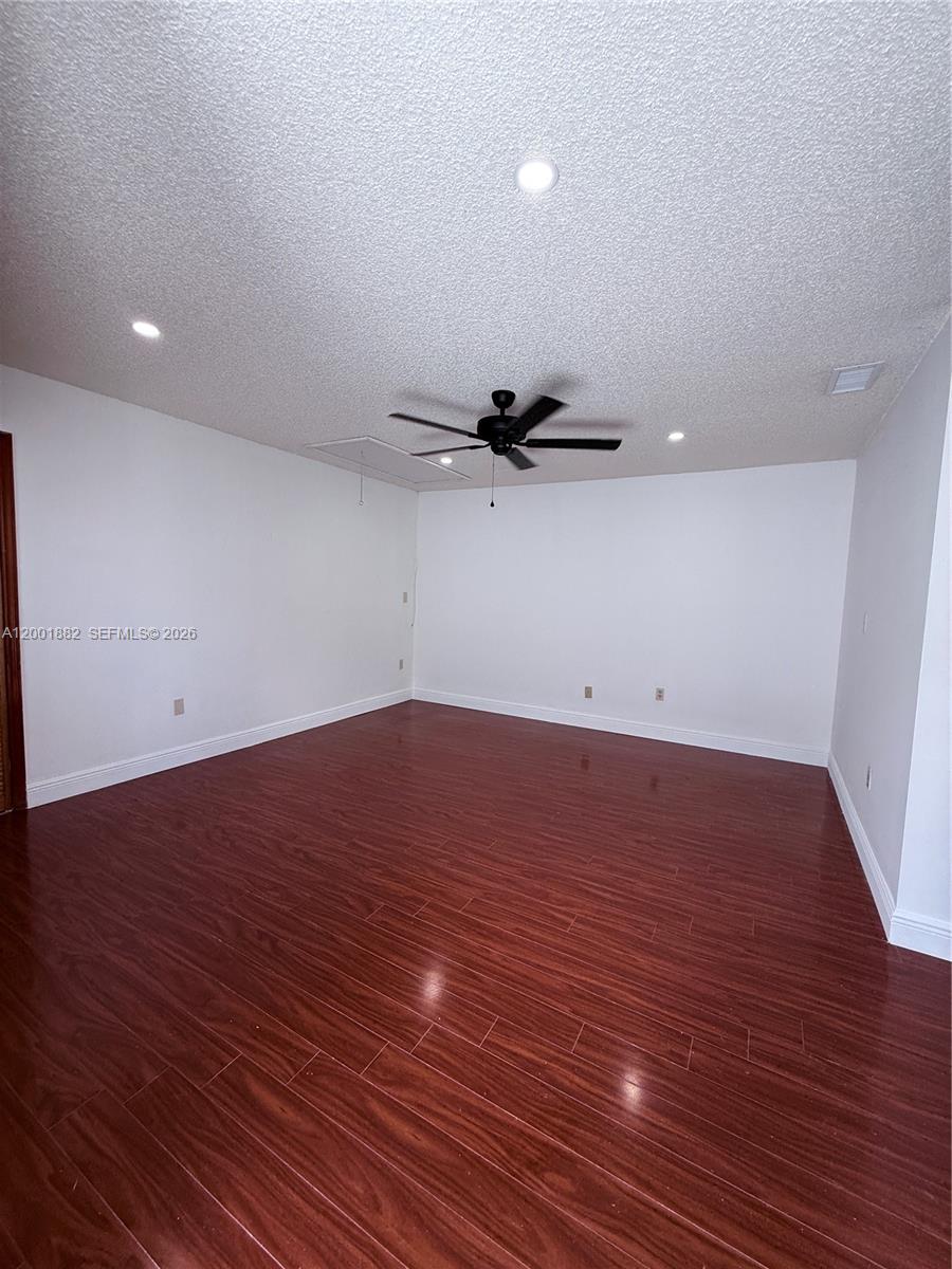 An empty room features dark wood-look flooring, white walls, and a ceiling fan — 14220 SW 53rd St # B, Miami FL 33175, MIAMI, FL
