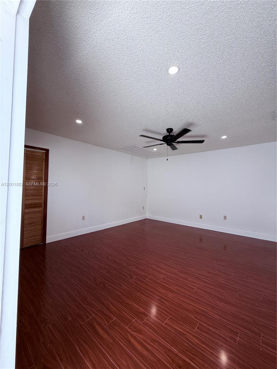 An empty room features dark wood-look flooring, white walls, and a black ceiling fan — 14220 SW 53rd St # B, Miami FL 33175, MIAMI, FL