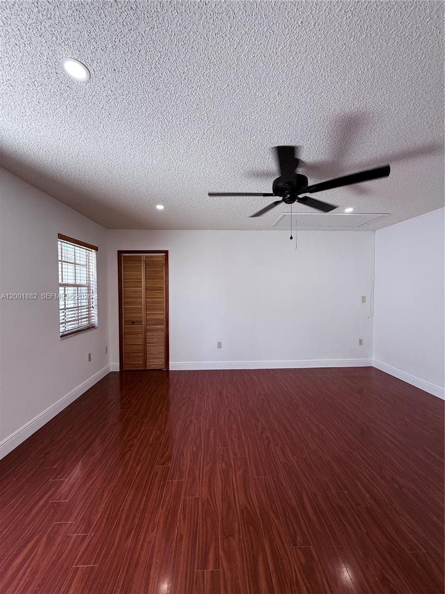 An empty room features wood-look flooring, white walls, a ceiling fan, and a louvered door — 14220 SW 53rd St # B, Miami FL 33175, MIAMI, FL