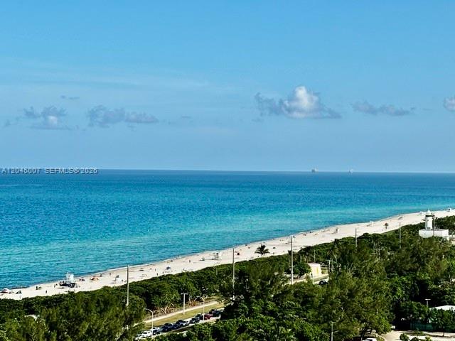 An elevated view of a sandy beach, turquoise ocean, and lush green trees — 100 Bayview Dr # 2124, Sunny Isles Beach FL 33160, SUNNY ISLES BEACH, FL