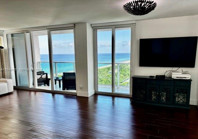A living room features dark wood flooring, a large television, and sliding doors overlooking the ocean — 100 Bayview Dr # 2124, Sunny Isles Beach FL 33160, SUNNY ISLES BEACH, FL