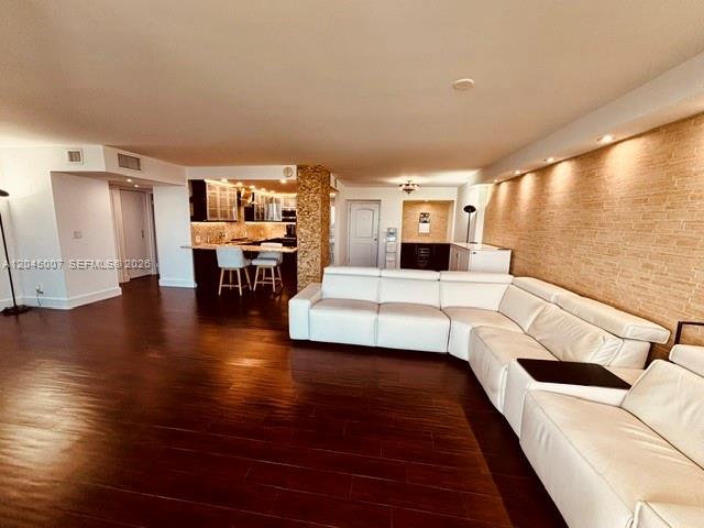 A spacious living room features dark wood flooring, a large white sectional sofa, and an open kitchen — 100 Bayview Dr # 2124, Sunny Isles Beach FL 33160, SUNNY ISLES BEACH, FL