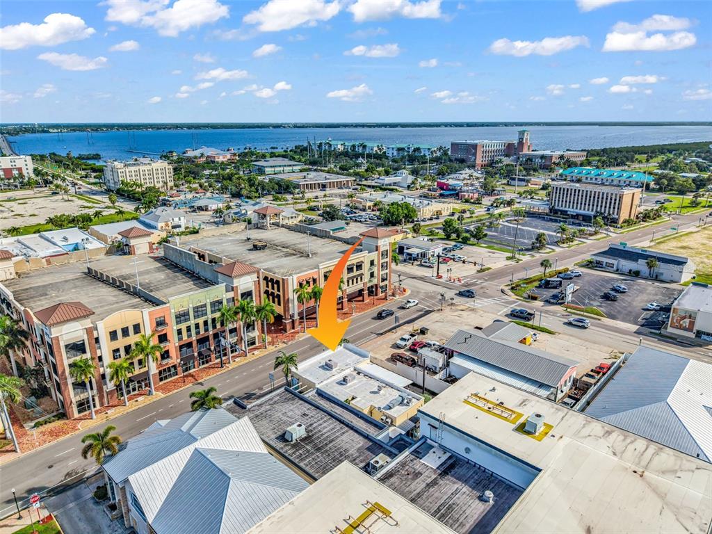 An aerial view shows a commercial building with a flat roof and an orange arrow — 111 W OLYMPIA AVENUE, PUNTA GORDA, FL
