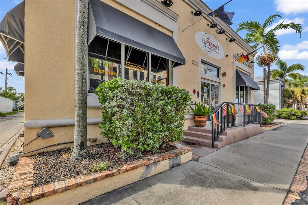Exterior view of a restaurant building with a brick-bordered garden and a small staircase — 111 W OLYMPIA AVENUE, PUNTA GORDA, FL