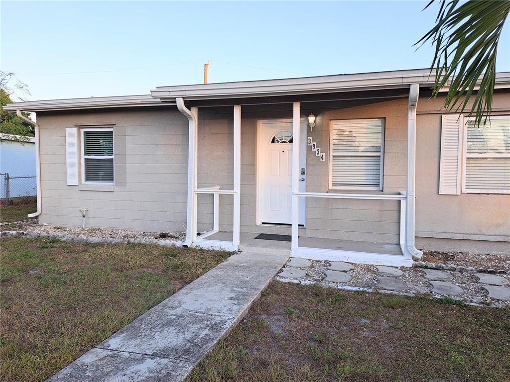 A single-story house with gray siding, a white front door, and a small covered porch — 3934 CONWAY BOULEVARD, PORT CHARLOTTE, FL