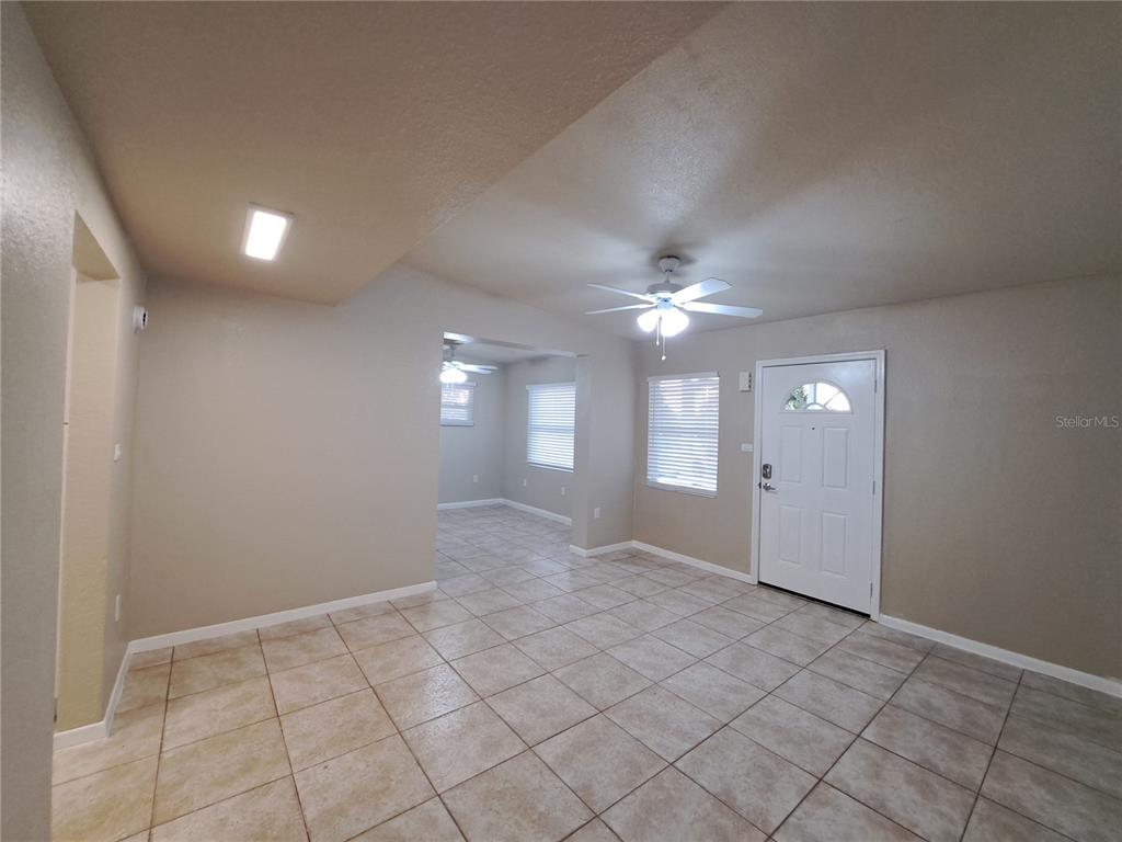 An interior view of a room with tiled floors, a ceiling fan, and a front door — 3934 CONWAY BOULEVARD, PORT CHARLOTTE, FL
