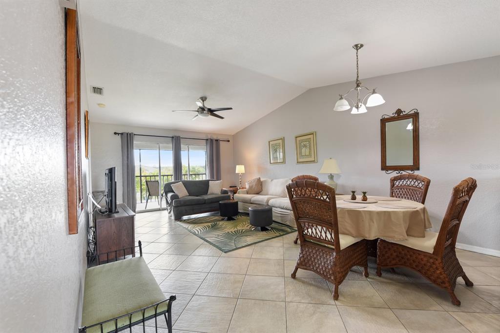 A living and dining area with tile floors, wicker chairs, and a sliding glass door — 449 ROYAL POINCIANA UNIT 221, PUNTA GORDA, FL