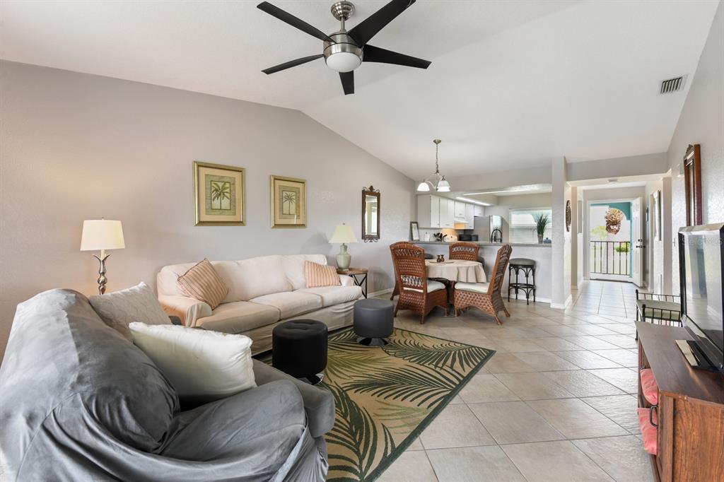 A living room and dining area with tile floors, a ceiling fan, and wicker chairs — 449 ROYAL POINCIANA UNIT 221, PUNTA GORDA, FL
