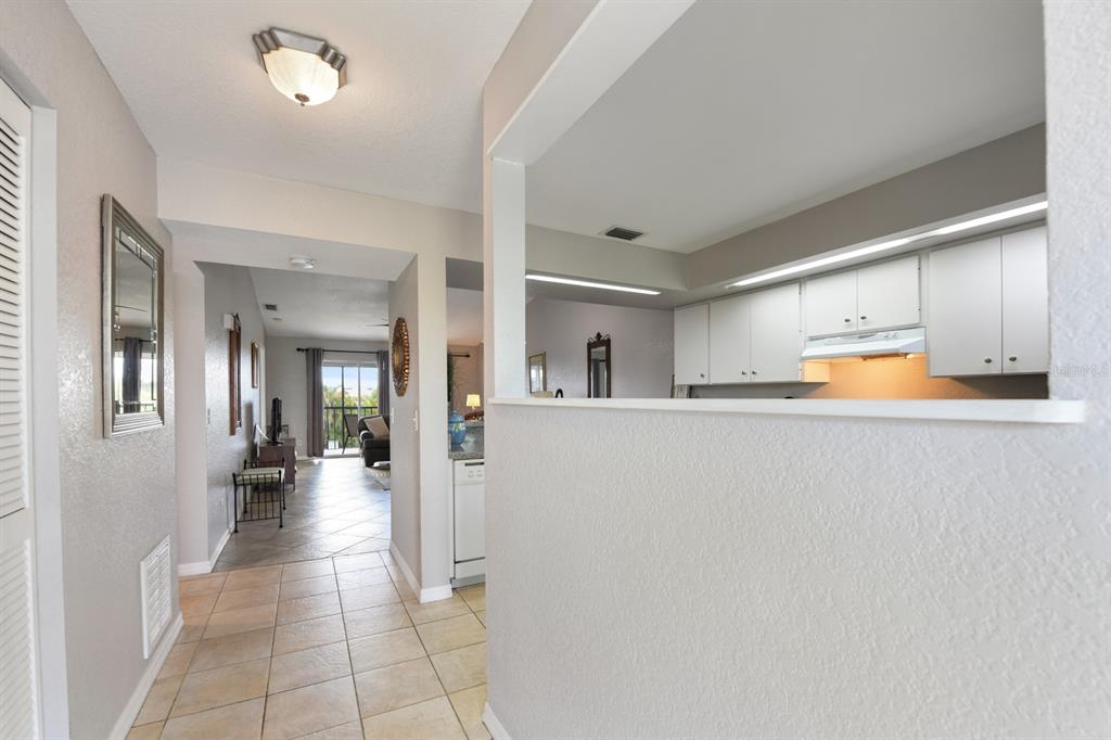 A tiled hallway leads to a living area, with a kitchen pass-through window on the right — 449 ROYAL POINCIANA UNIT 221, PUNTA GORDA, FL