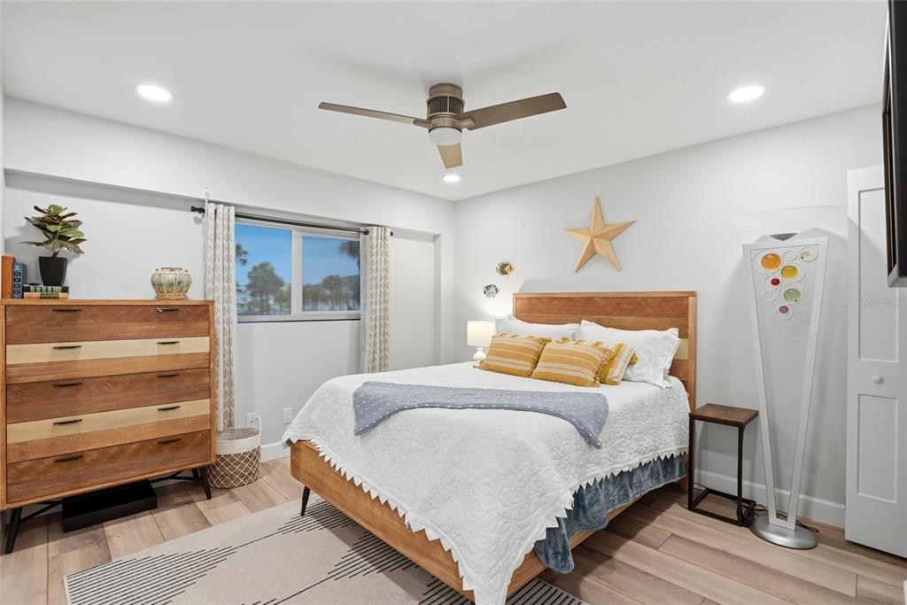 A bedroom features a wooden bed frame, a matching dresser, and a tall floor lamp — 363 PINELLAS BAYWAY S UNIT 29, TIERRA VERDE, FL