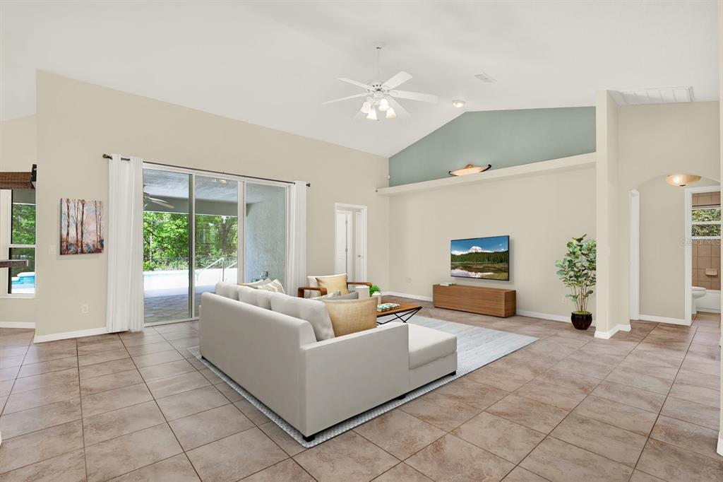 A living room with tile floors, a vaulted ceiling, and a sliding door to a pool — 1155 E BLUEBIRD COURT, HERNANDO, FL