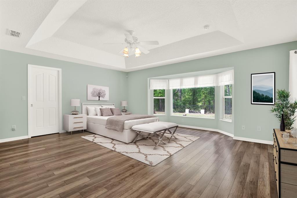 A bedroom with light green walls, a tray ceiling, a bay window, and wood flooring — 1155 E BLUEBIRD COURT, HERNANDO, FL