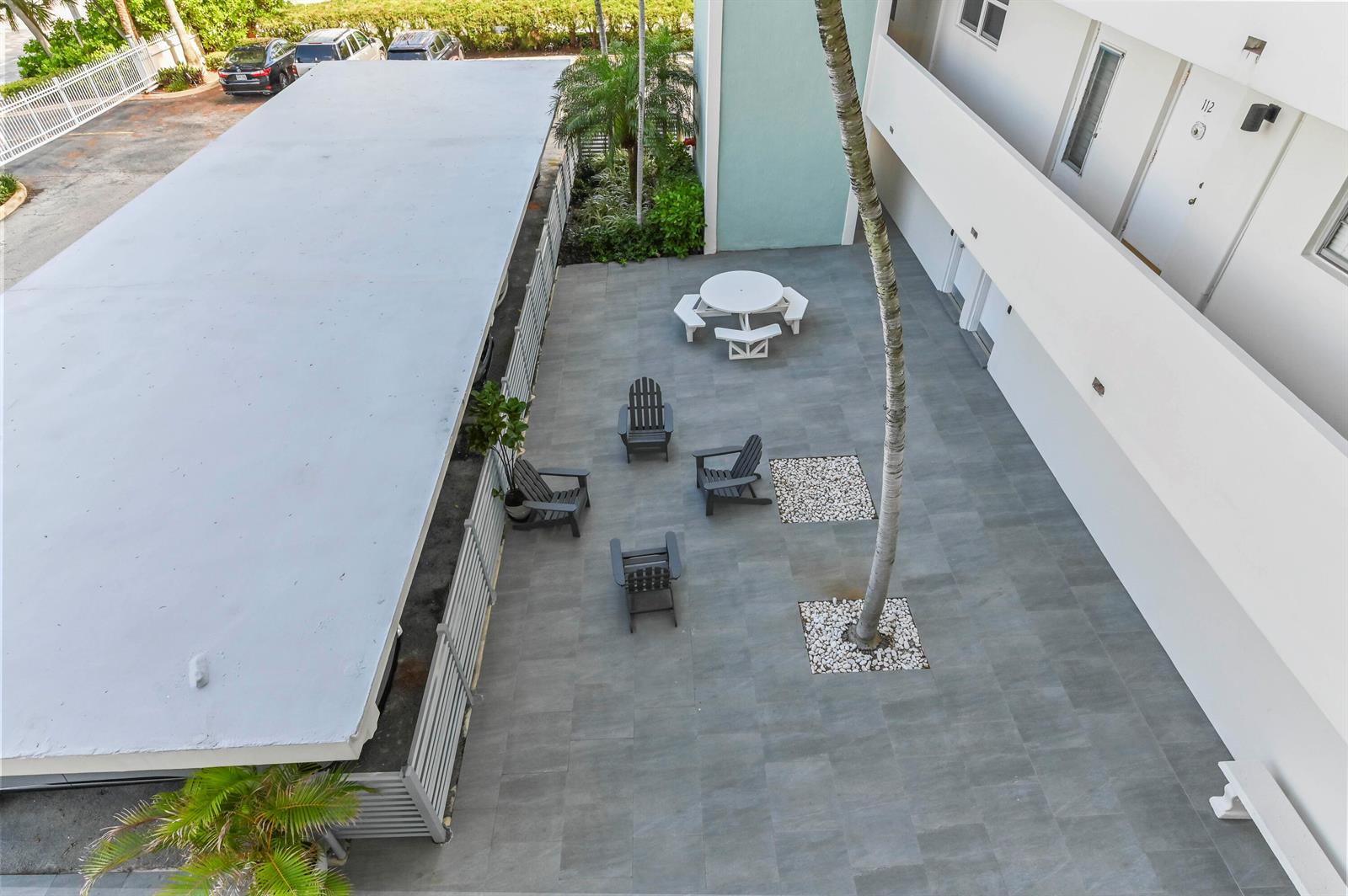 An aerial view shows a paved courtyard with outdoor seating, a palm tree, and parking — 1630 N Ocean Boulevard # 215, Pompano Beach FL 33062, POMPANO BEACH, FL