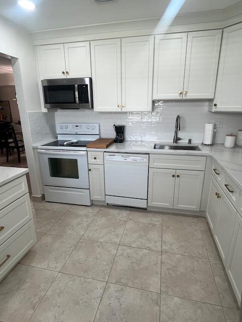 A kitchen features white cabinetry, stainless steel appliances, a subway tile backsplash, and tiled flooring — 27 Capri # A, Delray Beach FL 33484, DELRAY BEACH, FL