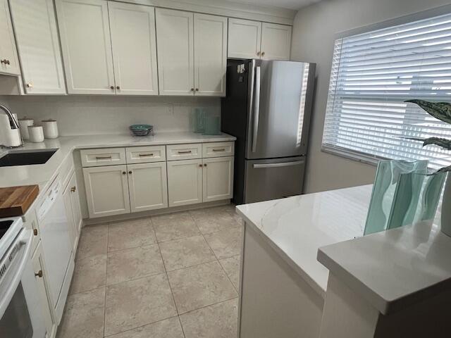 A kitchen features white cabinets, stainless steel appliances, and a white quartz countertop island — 27 Capri # A, Delray Beach FL 33484, DELRAY BEACH, FL