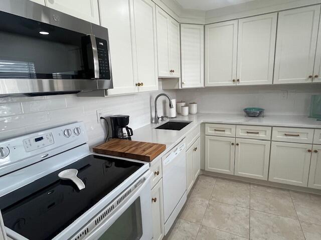 A kitchen features white cabinets, stainless steel appliances, and a light-colored tile floor — 27 Capri # A, Delray Beach FL 33484, DELRAY BEACH, FL