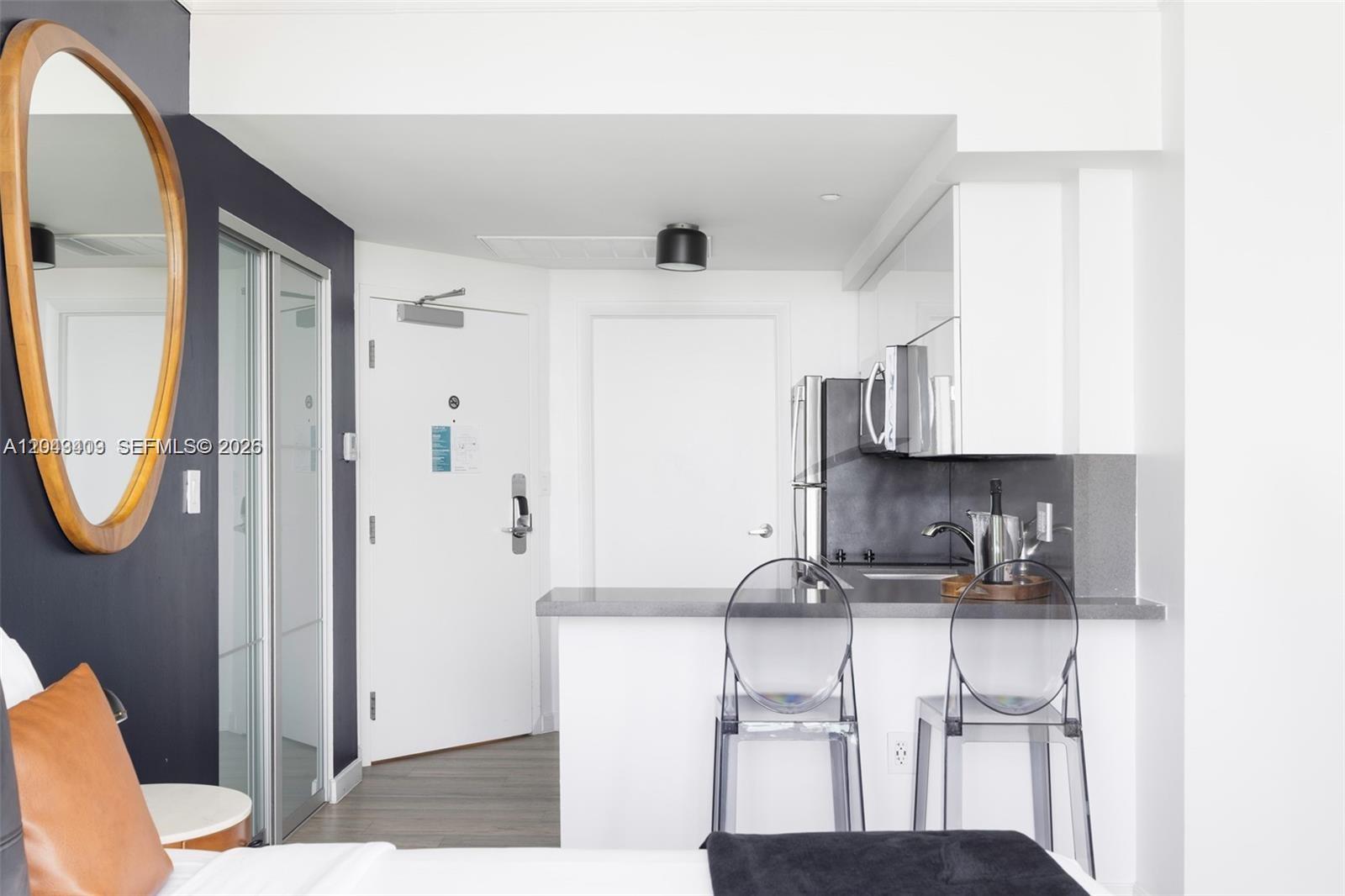 A studio apartment features a kitchen with a breakfast bar, two transparent chairs, and a mirror — 2889 Mcfarlane Rd # 1912, Miami FL 33133, MIAMI, FL