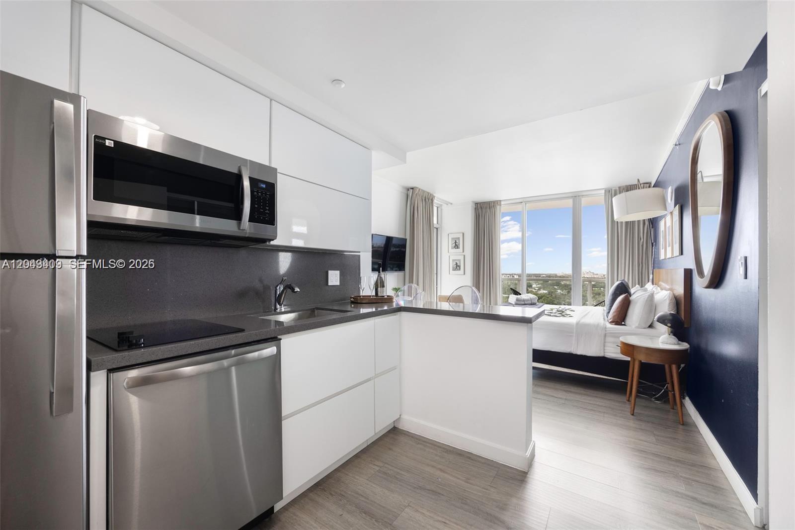A studio apartment features a modern kitchen with stainless steel appliances and a bedroom area — 2889 Mcfarlane Rd # 1912, Miami FL 33133, MIAMI, FL