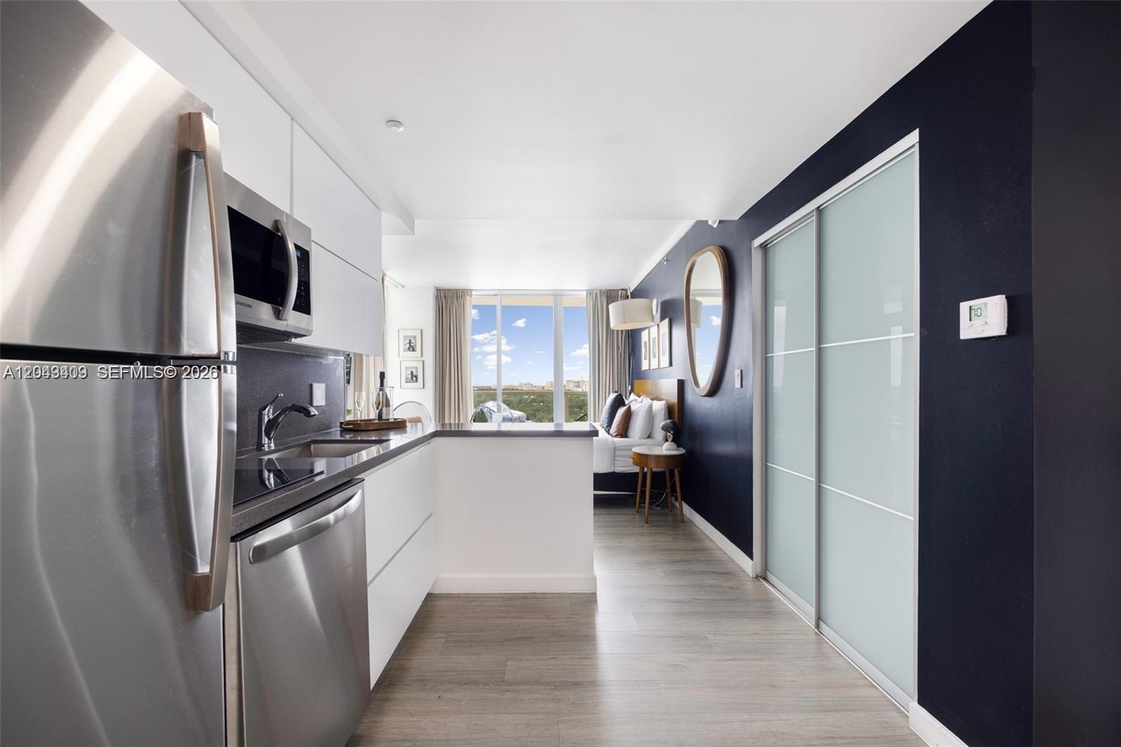 A modern studio apartment features a kitchen with stainless steel appliances and a bedroom area — 2889 Mcfarlane Rd # 1912, Miami FL 33133, MIAMI, FL