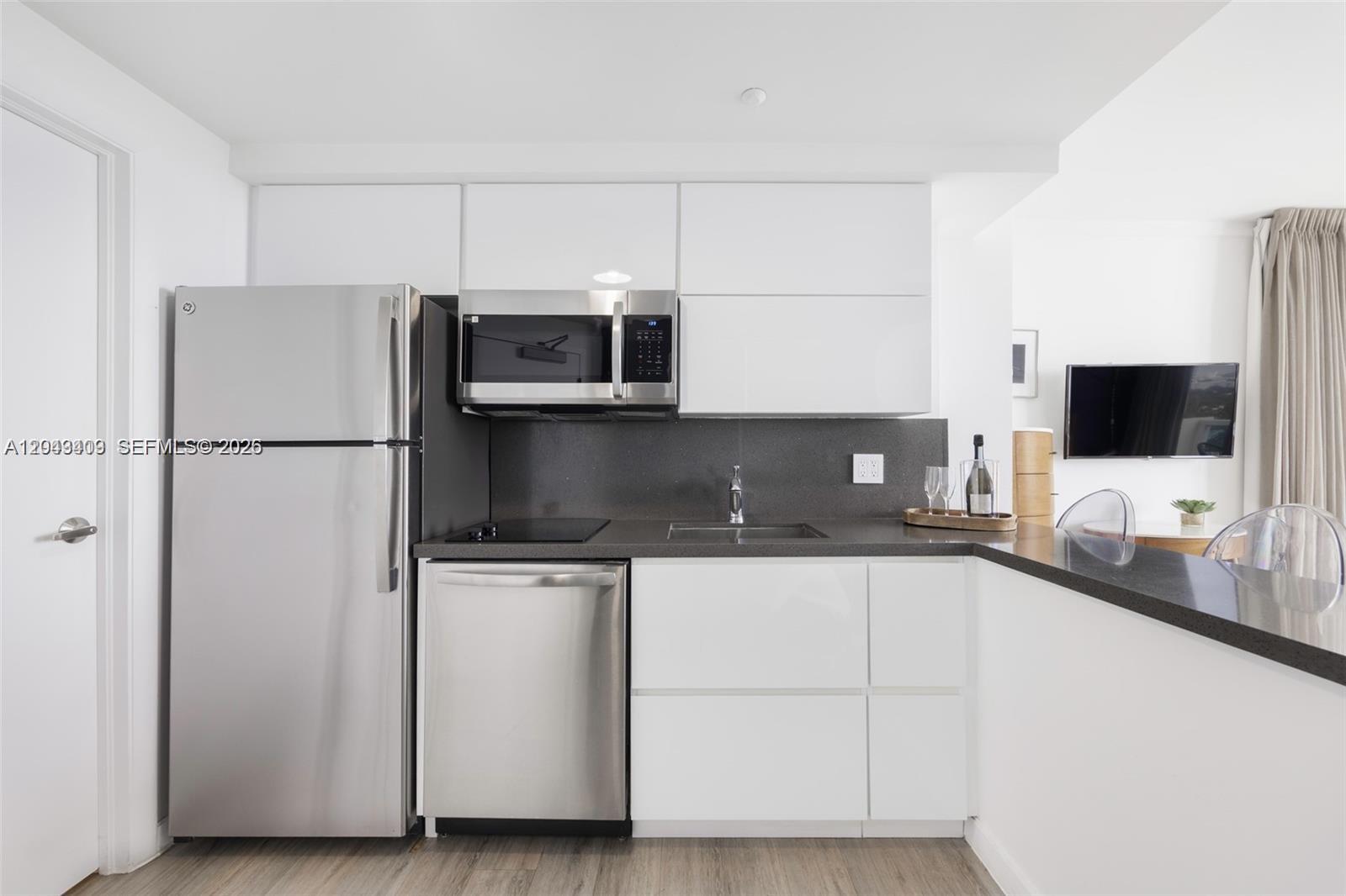 A modern kitchen features white cabinets, stainless steel appliances, and dark gray countertops — 2889 Mcfarlane Rd # 1912, Miami FL 33133, MIAMI, FL