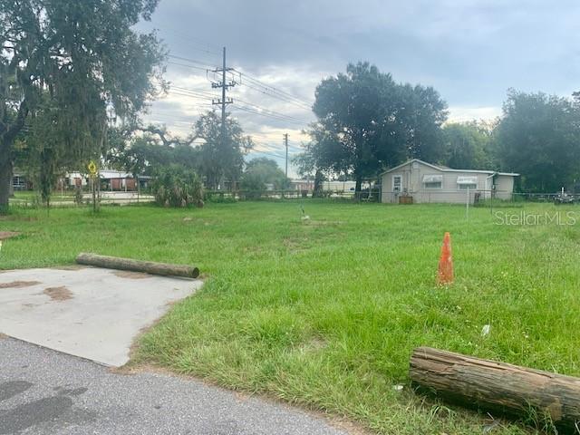 A grassy vacant lot features a concrete pad, a wooden log, and a traffic cone — 2904 PARK STREET, EATON PARK, FL