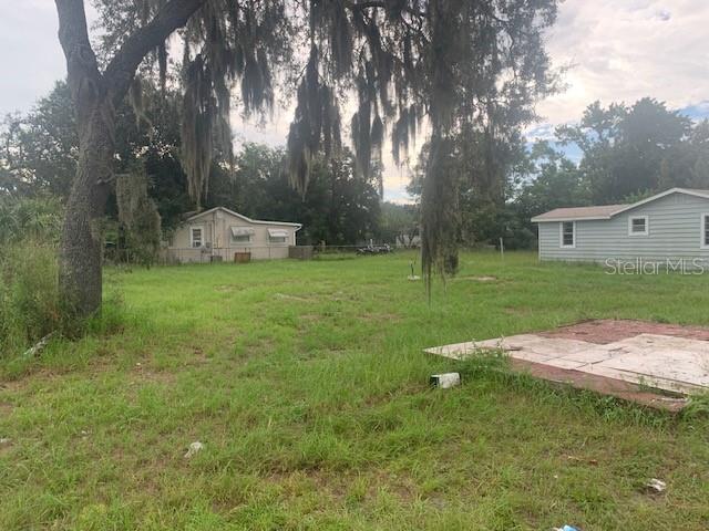 A grassy backyard features a large tree with Spanish moss and two small residential buildings — 2904 PARK STREET, EATON PARK, FL