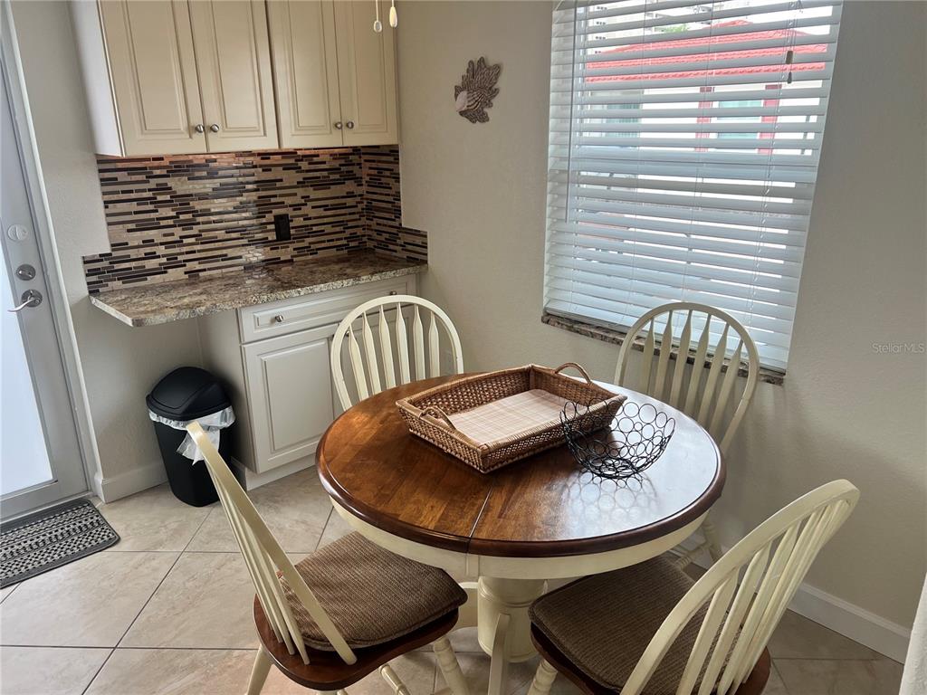 A kitchen breakfast nook features a round wooden table, four chairs, and tiled flooring — 6154 MIDNIGHT PASS ROAD UNIT B07, SARASOTA, FL