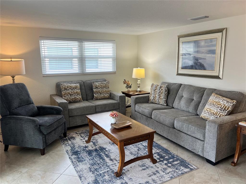 A living room features gray sofas, a recliner, a wooden coffee table, and a patterned rug — 6154 MIDNIGHT PASS ROAD UNIT B07, SARASOTA, FL