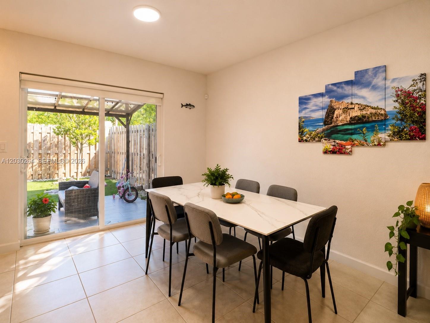 A dining room with a marble-topped table, gray chairs, and a sliding door to a patio — 12159 NW 23rd Ct # 12159, Miami FL 33167, MIAMI, FL