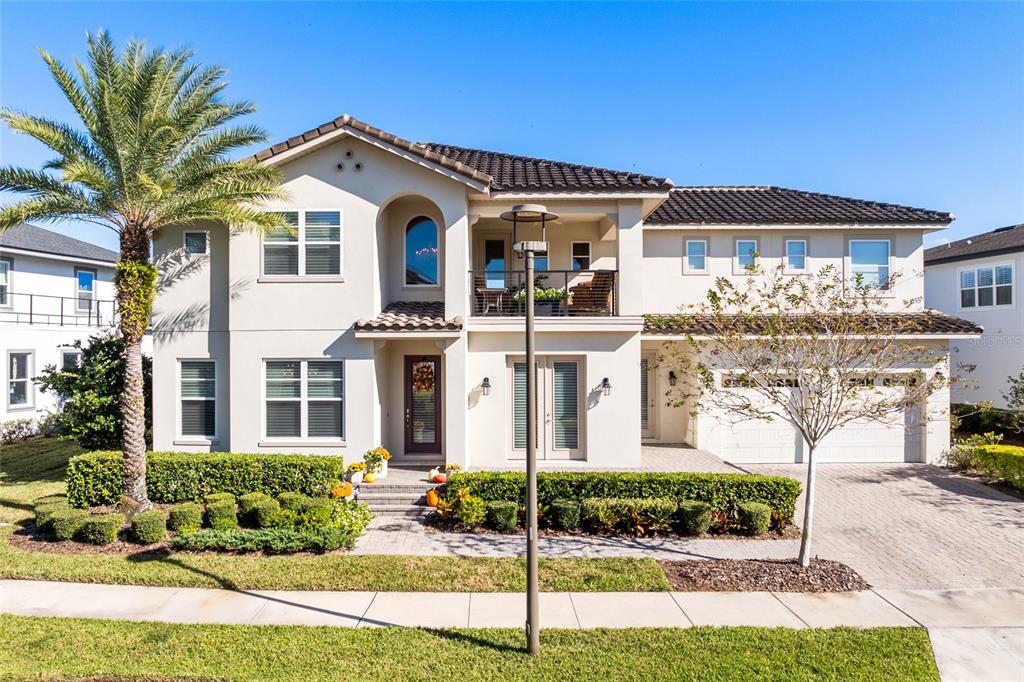 A two-story stucco house with a tile roof, a balcony, and a paved driveway — 14153 CORRIGAN AVENUE, ORLANDO, FL