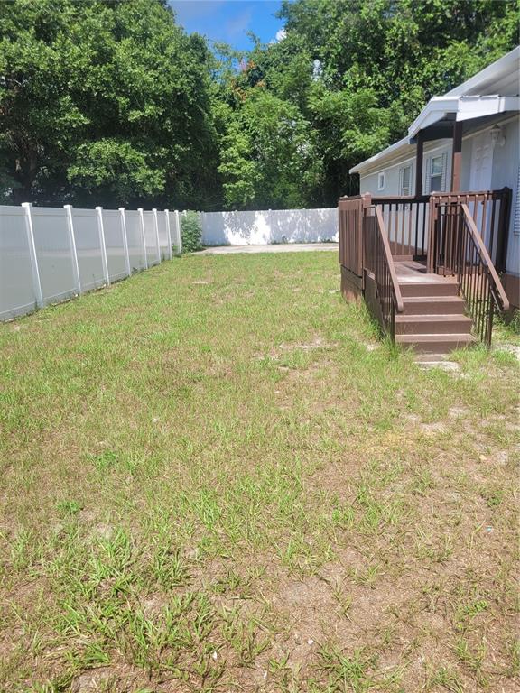 A backyard with a white vinyl fence and a wooden deck attached to a house — 13164 SE 102ND TERRACE, OCKLAWAHA, FL