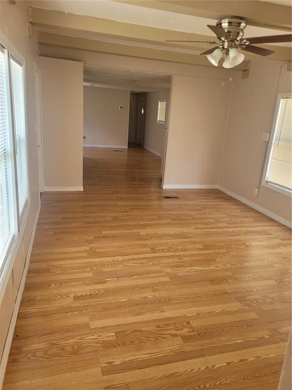 An empty living room features light wood-look flooring, beige walls, and a ceiling fan — 13164 SE 102ND TERRACE, OCKLAWAHA, FL