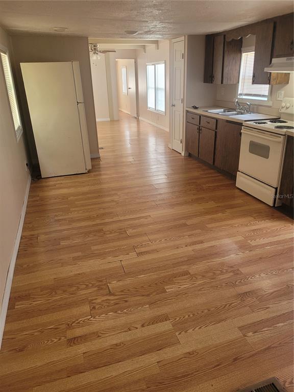 A kitchen with wood-look flooring, dark wood cabinets, a white refrigerator, and a white stove — 13164 SE 102ND TERRACE, OCKLAWAHA, FL