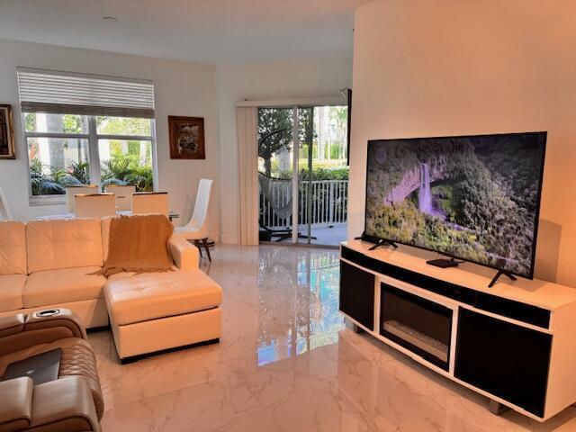 A living room features a white sectional sofa, a television console with a fireplace, and tile flooring — 804 E Windward Way # 103, Lantana FL 33462, LANTANA, FL
