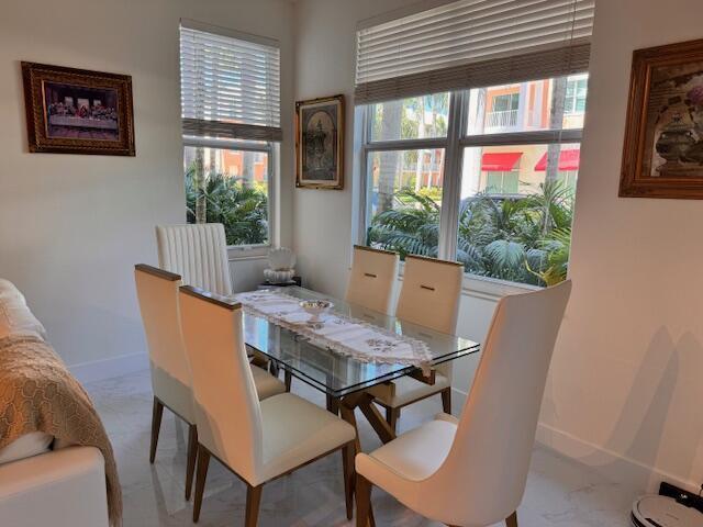 A dining room features a glass-topped table, six upholstered chairs, and large windows with blinds — 804 E Windward Way # 103, Lantana FL 33462, LANTANA, FL