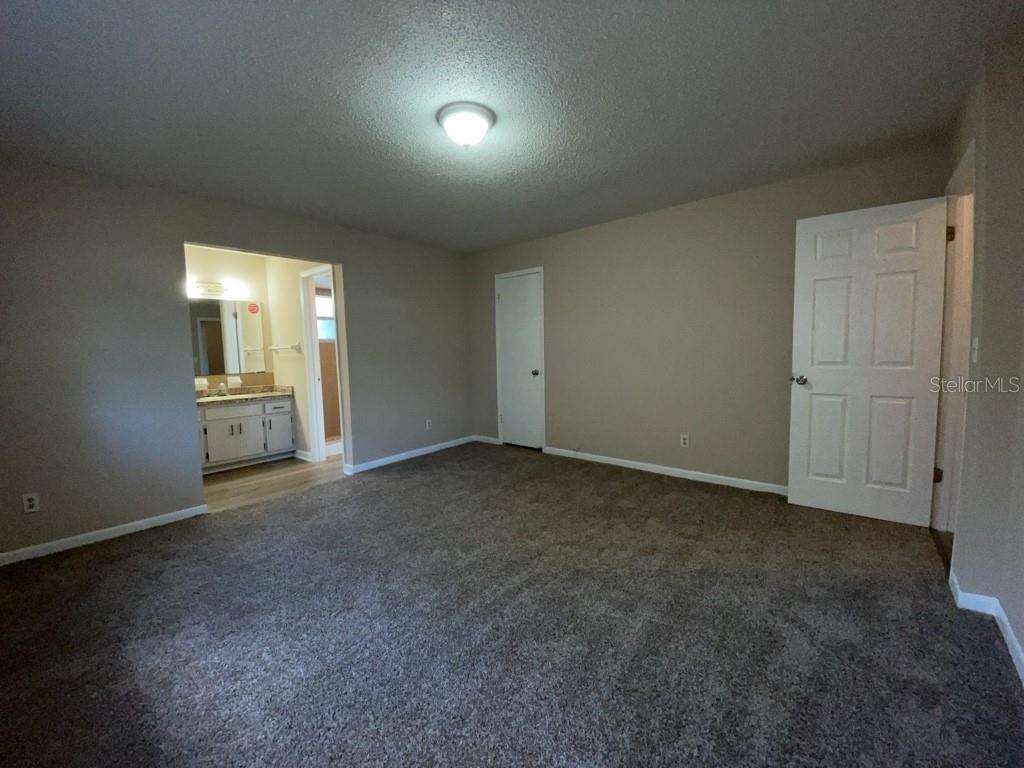 A carpeted bedroom features a doorway leading to an attached bathroom with a vanity — 10910 SE 51ST COURT, BELLEVIEW, FL