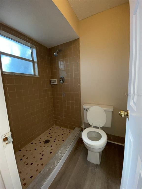 A bathroom features a walk-in shower with tan tiled walls and a white toilet — 10910 SE 51ST COURT, BELLEVIEW, FL