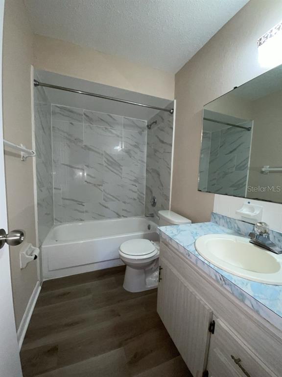 A bathroom features a marble-tiled shower-tub combo, a white vanity, and wood-look flooring — 10910 SE 51ST COURT, BELLEVIEW, FL