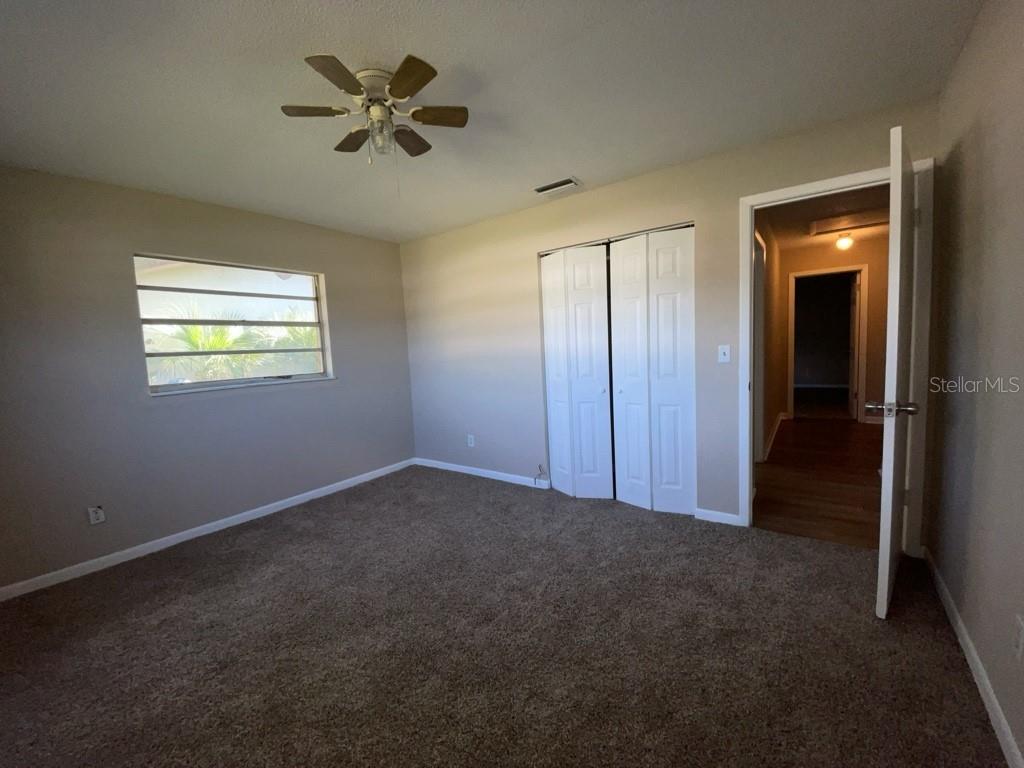 A bedroom with beige walls, brown carpet, a ceiling fan, and a white closet door — 10910 SE 51ST COURT, BELLEVIEW, FL