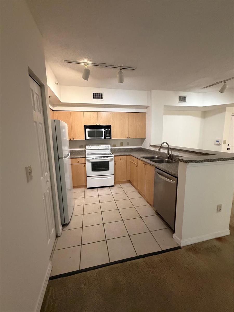 A kitchen features light wood cabinets, white appliances, a double sink, and tiled flooring — 2351 W Preserve Way # 104, Miramar FL 33025, MIRAMAR, FL