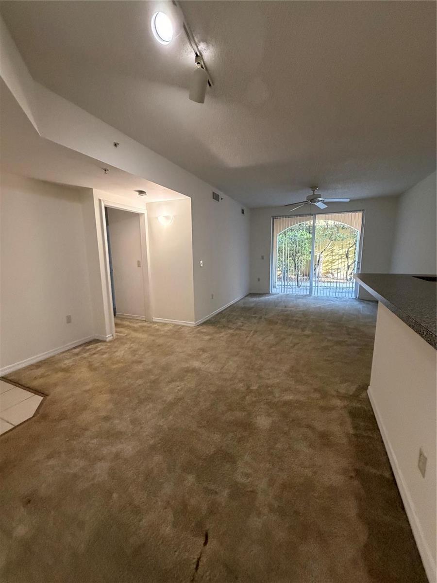 A carpeted living room with a ceiling fan, sliding glass doors, and a kitchen counter — 2351 W Preserve Way # 104, Miramar FL 33025, MIRAMAR, FL